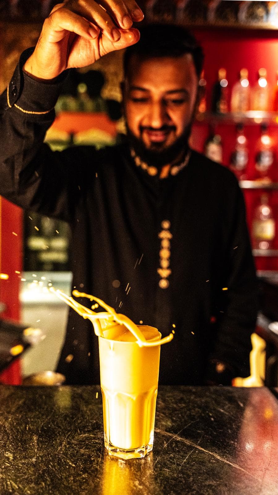 Lassi à la mangue versé dans un verre givré, éclaboussures de lait