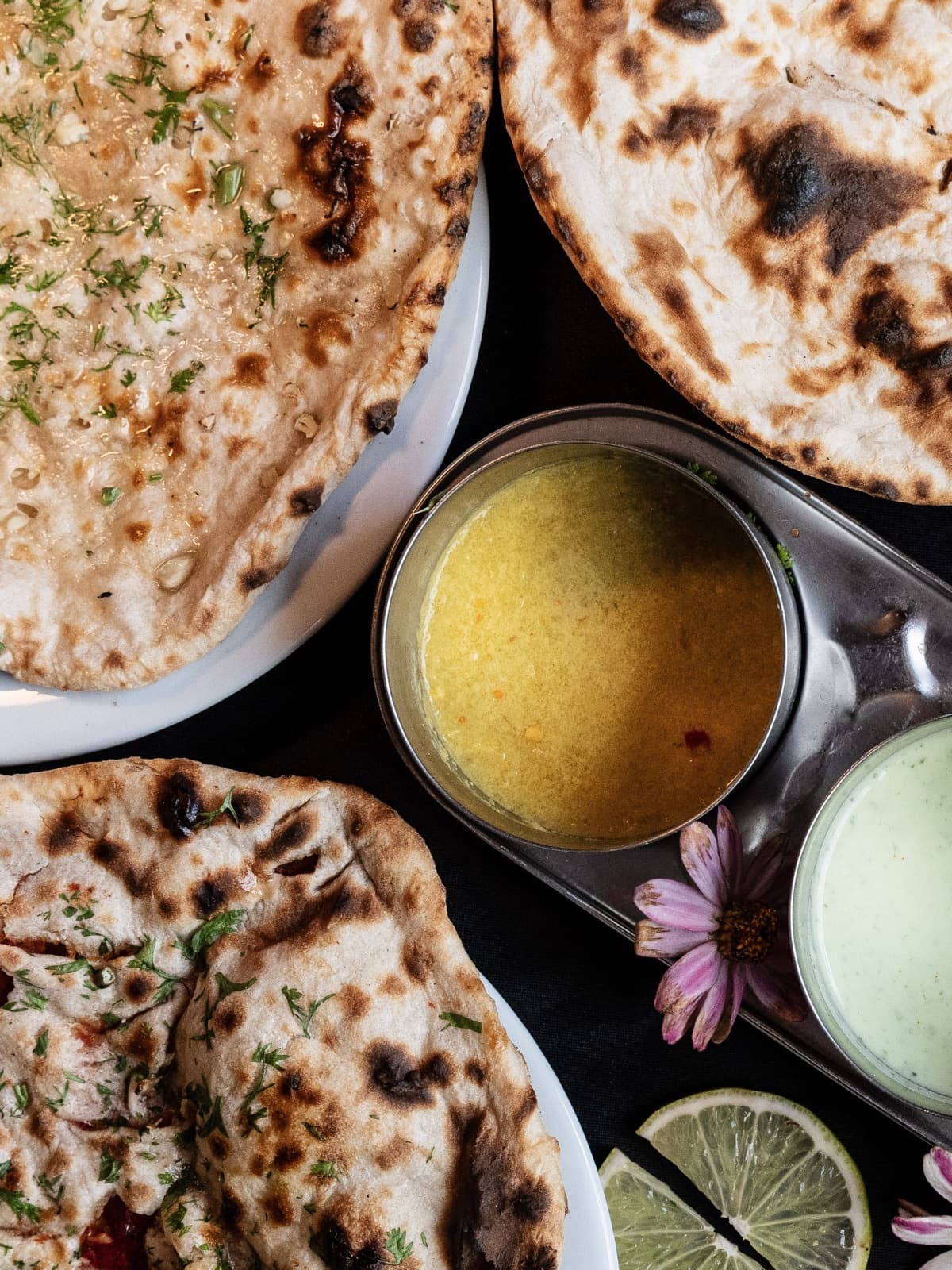 Assortiment de nans du tandoor — nature, coriandre et keema — avec dal et raïta