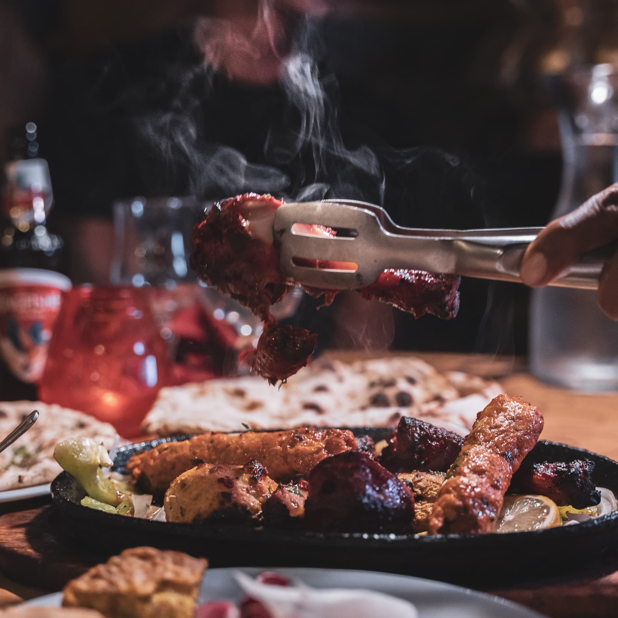 Mix grill pakistanais grésillant sorti du tandoor, vapeur et braises