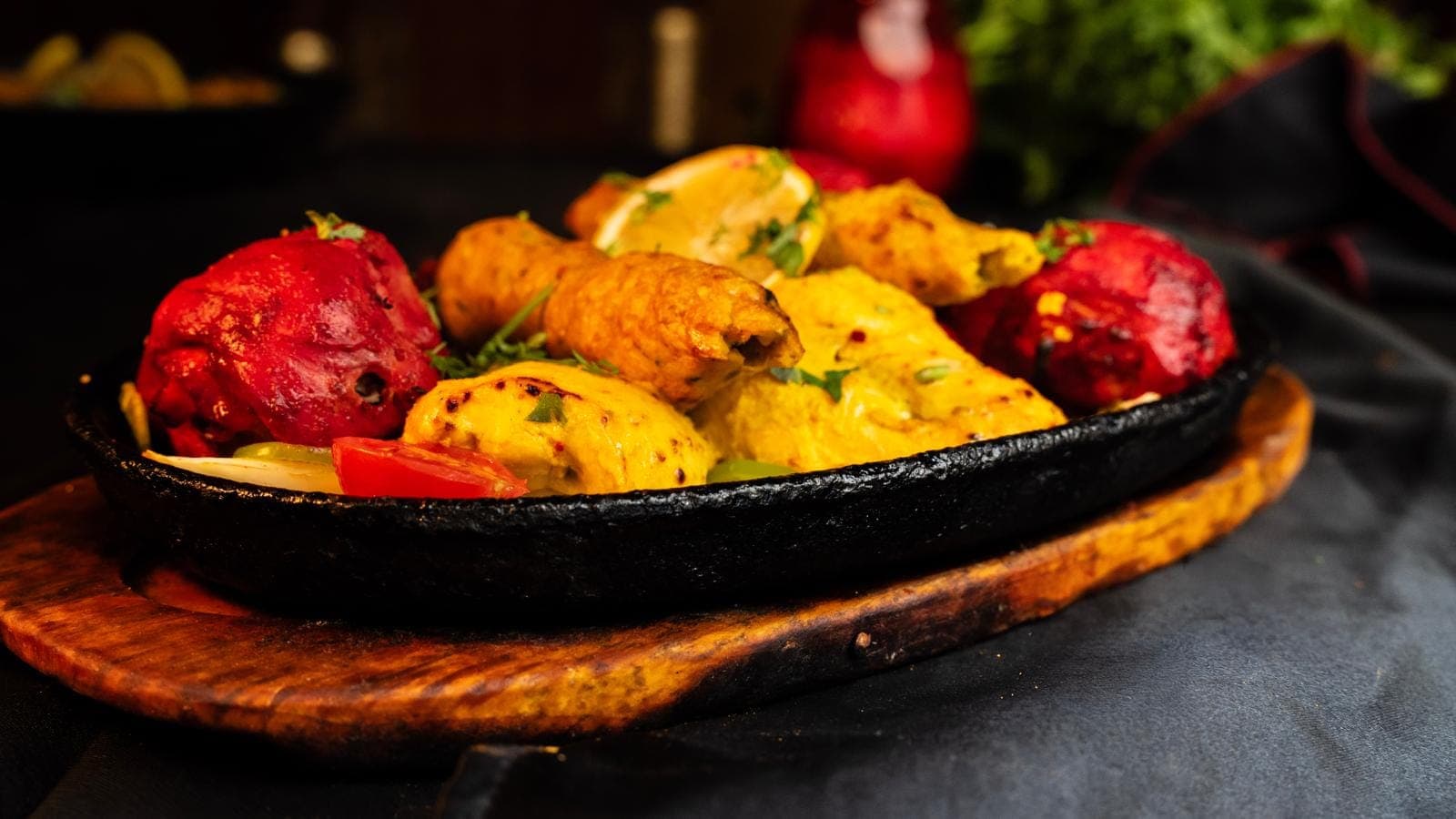Assortiment de viandes marinées grillées au tandoor, servi grésillant sur sa plaque en fonte